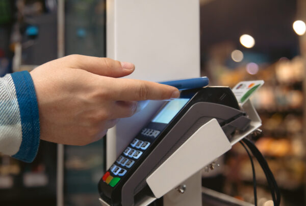 Close up of male hand holding smartphone in payment terminal, Paypass technology concept.