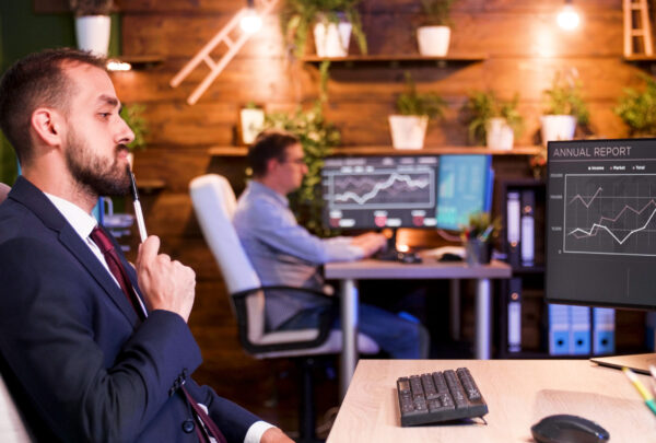 Businessman thinking in front of his monitors in the office late at night